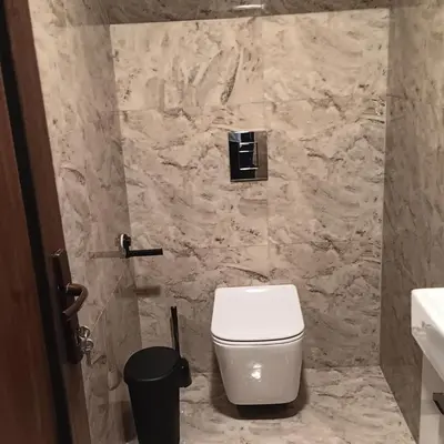 a bathroom with a white toilet and a stone wall at Valva vila in Luokesos Sen