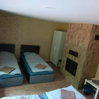 two beds in a room with a fireplace at Valva vila in Luokesos Sen
