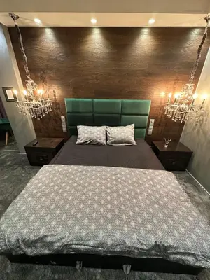 a bedroom with a bed with a green headboard and lights at B&M Mini jecuzzi Lovers room Self check-in in Vilnius