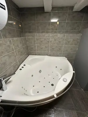 a bath tub in a bathroom with a tile wall at B&M Mini jecuzzi Lovers room Self check-in in Vilnius