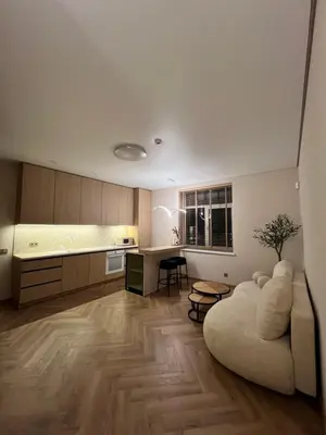 a living room with a couch and a kitchen at Apartamentai pirmame aukšte, miesto centre in Vilkaviškis