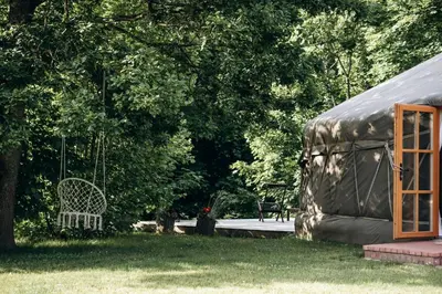 a swing in a yard next to a tent at Intimate Peaceful Yurt Surrounded by Nature in Lithuania in Jundeliškės