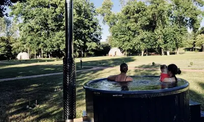 three people in a hot tub in a park at Intimate Peaceful Yurt Surrounded by Nature in Lithuania in Jundeliškės