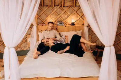 a man and two women laying on a bed in a yurt at Intimate Peaceful Yurt Surrounded by Nature in Lithuania in Jundeliškės