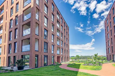 a red brick building with a green lawn in front at River View Apartment with free parking in Kaunas