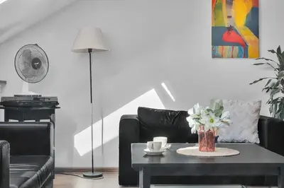 a living room with a black couch and a table with flowers at Vilnius Old Town Amber Penthouse in Vilnius