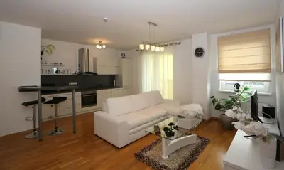 a living room with a white couch and a kitchen at Apartamentai Panevezys in Panevėžys
