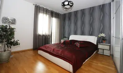 a bedroom with a bed with a red comforter at Apartamentai Panevezys in Panevėžys
