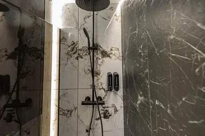 a shower in a bathroom with a damaged wall at Castle Town Kaunas Apartaments in Kaunas