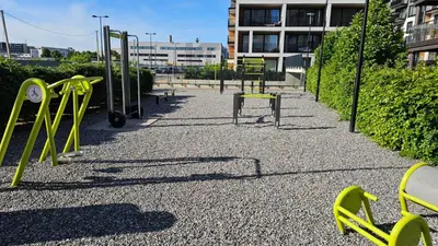 an empty playground with yellow equipment in front of a building at Castle Town Kaunas Apartaments in Kaunas
