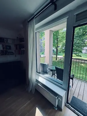 a room with a window and a balcony with a table at Cozy Ozo Park Apartment, Pet Friendly with Workspace in Vilnius