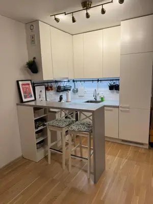 a kitchen with white cabinets and a table with stools at Cozy Ozo Park Apartment, Pet Friendly with Workspace in Vilnius