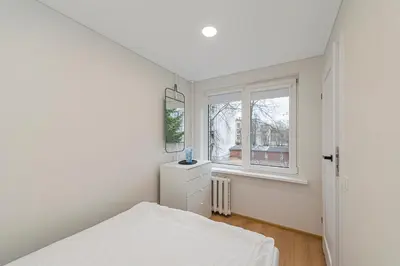 a white bedroom with a bed and a window at Apartment Lampėdis by Polo Apartments in Kaunas