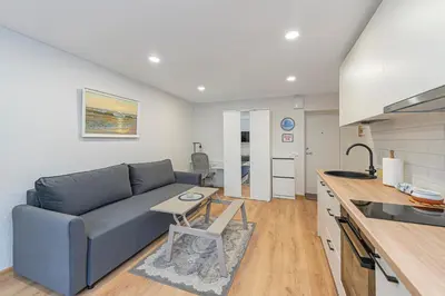 a living room with a blue couch and a kitchen at Apartment Lampėdis by Polo Apartments in Kaunas