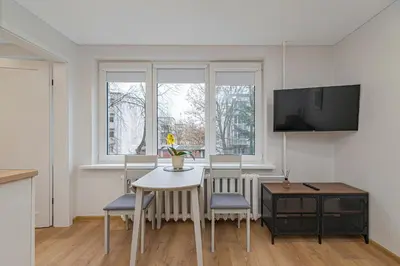 a living room with a table and chairs and a tv at Apartment Lampėdis by Polo Apartments in Kaunas