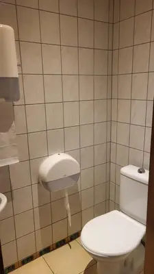 a bathroom with a white toilet and a tiled wall at Hunters Lounge Apartments