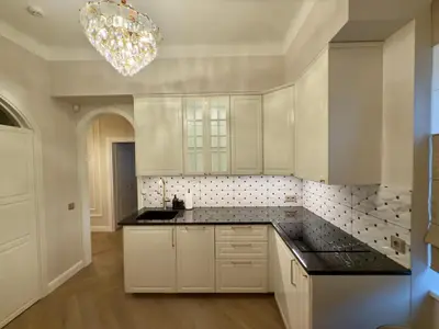 a kitchen with white cabinets and a chandelier at KR Apartment Kaunas in Kaunas