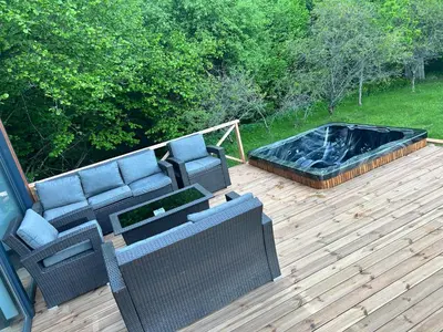a patio with a couch and a hot tub on a deck at Pasienio krantas in Velūnai