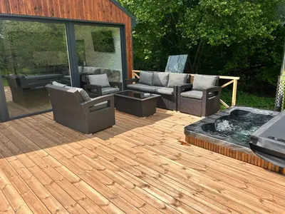 a wooden deck with chairs and a fire pit at Pasienio krantas in Velūnai