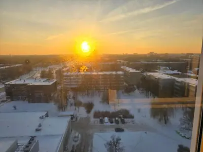 a sunset over a city with snow covered buildings at Apartaments Kaunas in Kaunas