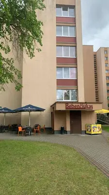 a building with tables and umbrellas in front of it at Butas Čiurlionio gatvėje in Pakopi