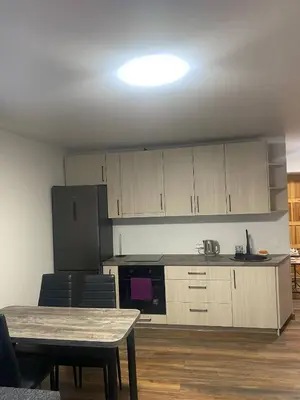 a kitchen with wooden cabinets and a table with chairs at Butas Čiurlionio gatvėje in Pakopi