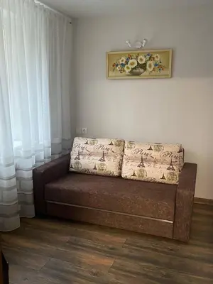 a couch sitting in a living room with curtains at Butas Čiurlionio gatvėje in Pakopi