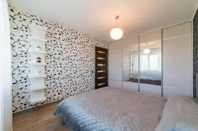 a bedroom with a bed and a wall with a mirror at Blue Sky Apartments in Šiauliai