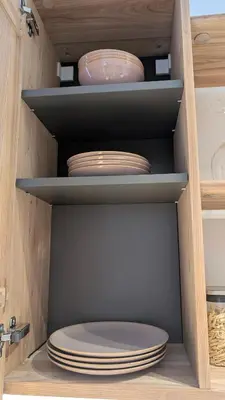 a stack of plates and bowls on shelves in a cabinet at Kaunas City Centre Apartment Self Check-In & AC in Kaunas