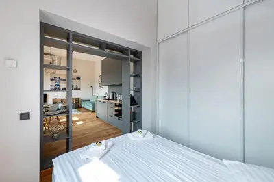 a bedroom with a bed and a kitchen in the background at Shanti barracks apartment #3 by Polo Apartments in Kaunas