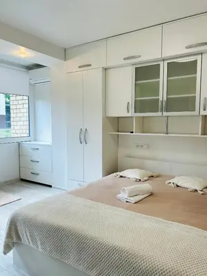 a bedroom with a large bed with white cabinets at Rugilės lelijų apartamentai in Birštonas