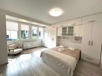 a bedroom with white cabinets and a bed and a chair at Rugilės lelijų apartamentai in Birštonas
