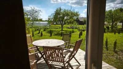 a table and chairs on a porch with a view of a yard at Gervių takas 1