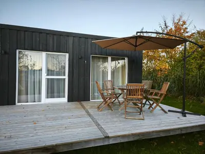 a deck with a table and chairs and an umbrella at Gervių takas 1