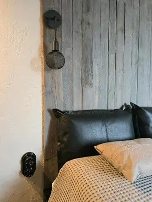 a black leather couch in a room with a wooden wall at Central Downtown Terrace Studio in Šiauliai