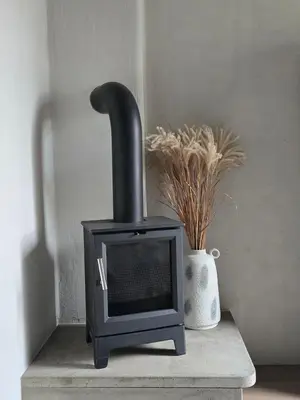 a black wood stove sitting on a table with a vase at Central Downtown Terrace Studio in Šiauliai