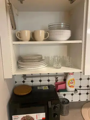 a cupboard with plates and bowls on top of a microwave at Vilnius Central Living – Jakšto place in Vilnius