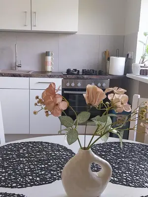 a vase with flowers on a table in a kitchen at Saulės miesto apartamentai in Šiauliai