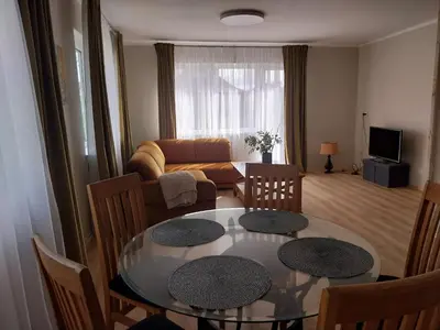 a living room with a table and a couch at Saulės miesto apartamentai in Šiauliai
