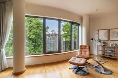 a living room with a chair and a large window at 2 Bedroom Apt with Balconies in Druskininkai