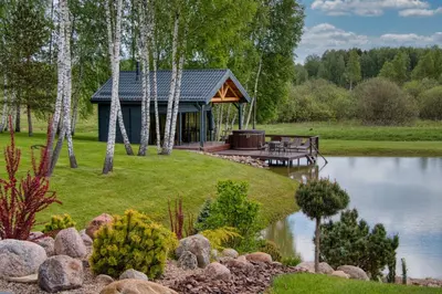 a cabin with a deck next to a lake at Žalesos pirtelė in Ažulauke