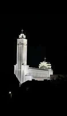 a large white building with a cross on top at night at Žaliakalnio panoramos apartamentai in Kaunas