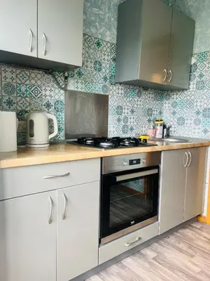 a kitchen with white cabinets and a stove top oven at Žaliakalnio panoramos apartamentai in Kaunas