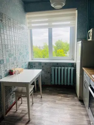 a kitchen with a table and a window and a radiator at Žaliakalnio panoramos apartamentai in Kaunas