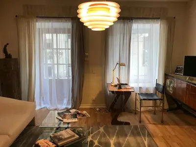 a living room with a desk and two windows at Artsy Retreat In The Heart Of Uzupis, Vilnius in Vilnius