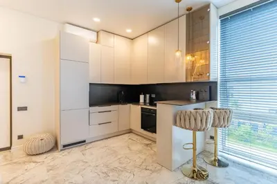 a kitchen with white cabinets and a bar stool at Studija 17 butai in Kaunas