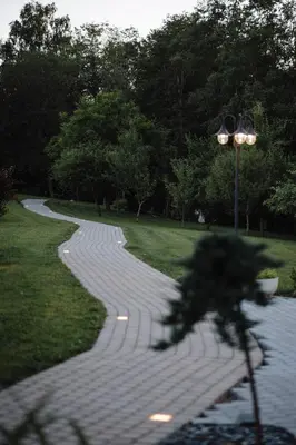 a walkway in a park with a bench and a street light at Vila Skodupė
