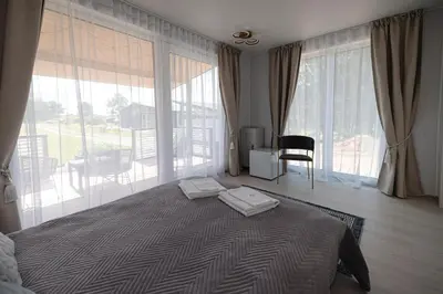 a bedroom with a large bed and large windows at Vila Skodupė