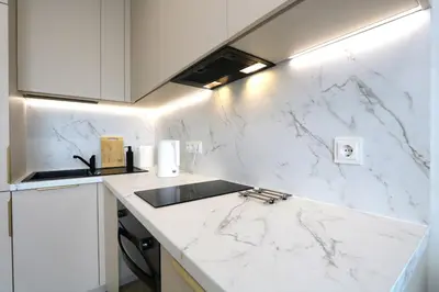 a white kitchen with a marble counter top at Flat for 2 or 1 with Free Parking and Fast Wi-Fi in Vilnius