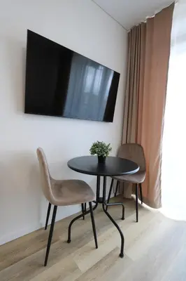 a table with a chair and a tv on a wall at Flat for 2 or 1 with Free Parking and Fast Wi-Fi in Vilnius